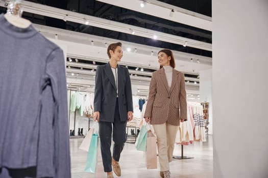 Young woman friends enjoying shopping together in big fashion shop mall. Purchases with discounts and sale concept