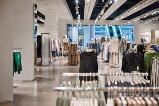 Clothing department store indoor interior in shopping mall. Lots of fashion casual outfit, fashion garment assortment on racks