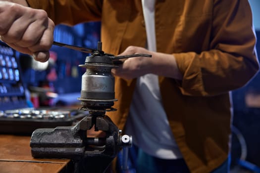 Professional bike mechanic disassembling and servicing bicycle internal-geared hub on manual vice in repair shop