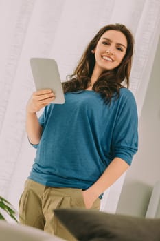 confident data specialist smiles while holding a digital tablet, embodying a balance between technical expertise and approachable demeanor. Her relaxed stance reflects her ease in the digital world
