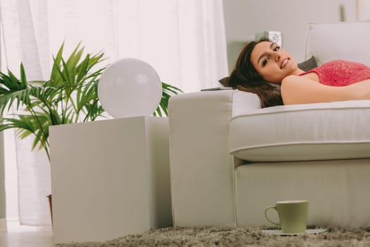 woman lies comfortably on a couch, embracing her vacation by simply resting. Unlike others eager to explore, she chooses to savor her free time, enjoying the luxury of doing nothing