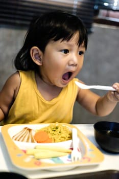Little boy open mouth eating soup from bowl with spoon.