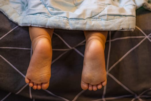 Legs of child sticking out from under the blankets.