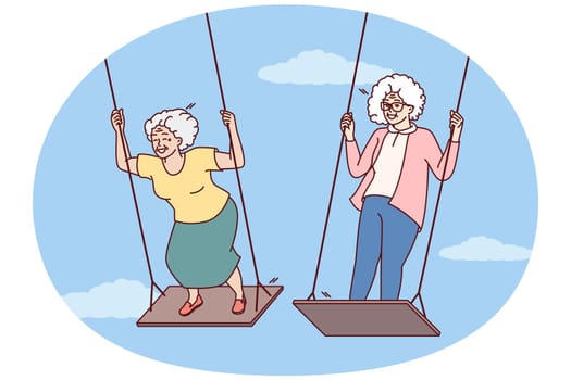 Two elderly women enjoy swinging and enjoying happy old age and not having to go to work. Carefree gray-haired female of retirement age remembers entertainment from youth and does not want to grow old