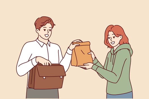 Man takes home-made lunch to work, from hands of loving wife caring for husband. Sandwich bag for delicious lunch for office employee who doesnt want to eat fast food or unhealthy processed foods.