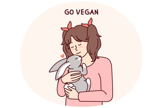 Little vegan older girl hugs rabbit that they wanted to use for food and cook for dinner. Concept of transition to healthy nutrition and promotion of vegan lifestyle from childhood and adolescence