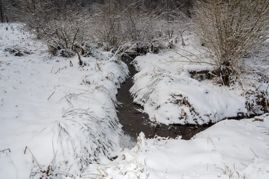 Small stream in the snow in wintertime
