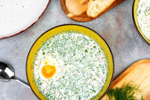 Delicious cold summer soup okroshka with boiled sausage in bowl