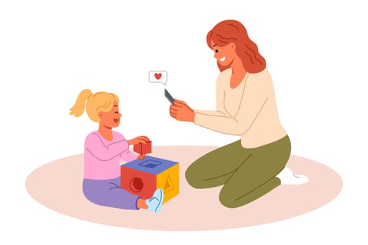 Happy mother takes photo of little daughter playing with blocks on mobile phone camera. Mother rejoices at success of pre-teen child demonstrating talent and readiness for development