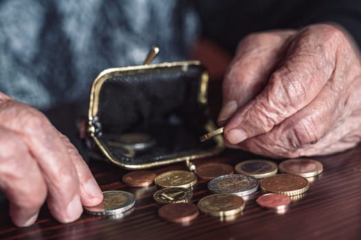 Detailed closeup photo of elderly 96 years old womans hands counting remaining coins from pension in her wallet after paying bills. Unsustainability of social transfers and pension system.
