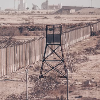 Fenced borderline, barbed wires and watchtower. Non-passable military zone.