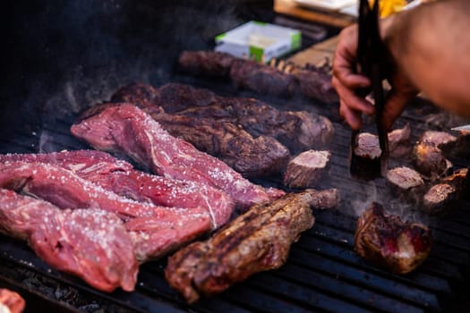 Some excellent pieces of Argentinian beef on a charcoal grill being prepared at open kitchen street food festival in Ljubljana, Slovenia
