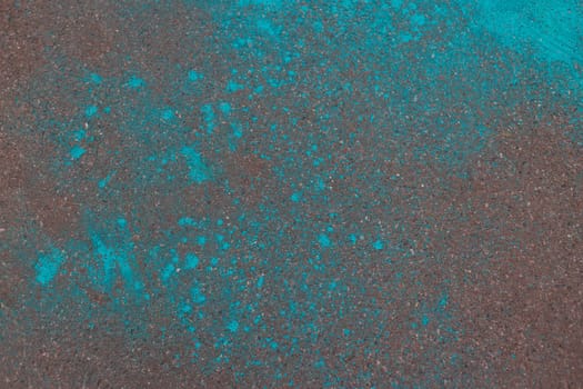 Multicolored dry blue paints on gray asphalt. Powder coating at the Holi festival. Place for inscription