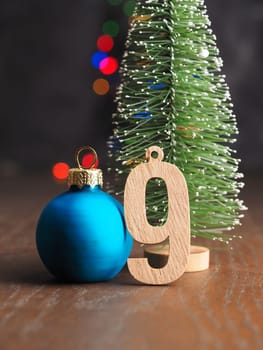 Ninth December Wooden number nine with old Christmas bauble on blurred Christmas lights