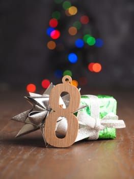 eighth December Wooden number one with pine cone on blurred Christmas lights
