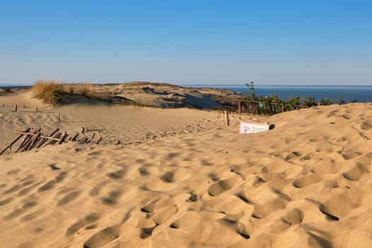 View of nordic dunes, footprints and bushes of Curonian spit, Nida, Klaipeda, Lithuania at sunset on early spring. Signs deep in sands