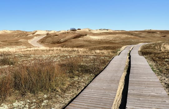 Nordic sand dunes and wooden pathway, Baltic sea, Curonian spit, Nida, Klaipeda, Lithuania at sunset. Lines, rhythm and patterns of shadows and hills