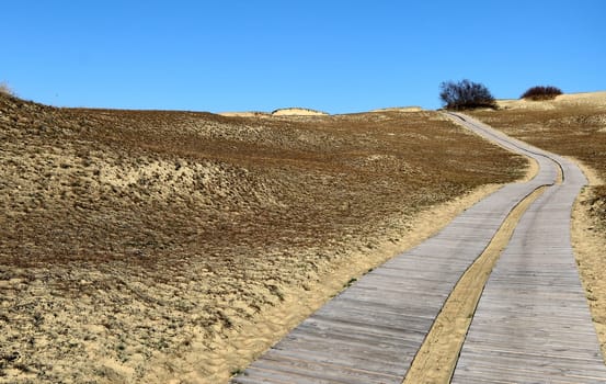 Nordic sand dunes and wooden pathway, Baltic sea, Curonian spit, Nida, Klaipeda, Lithuania at sunset. Lines, rhythm and patterns of shadows and hills