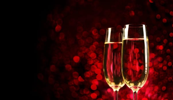 Two champagne glasses on sparkling red bokeh background. Celebration toast flutes. Valentine's day dinner invitation. Christmas and new year holiday party.