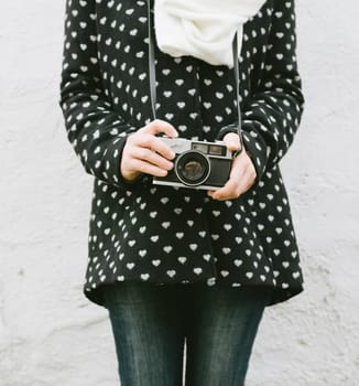 Young hipster woman holding vintage photo camera. Retro camera in girl hand closeup. Old fashion photography concept.