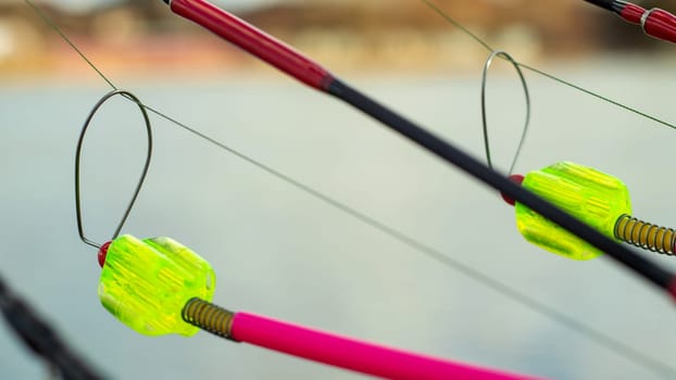 The bite alarm hangs on a fishing rod against the background of water. Fishing rod while fishing on the lake, river. Fishing tackle. Carp rod on a stand with a bite alarm on the line