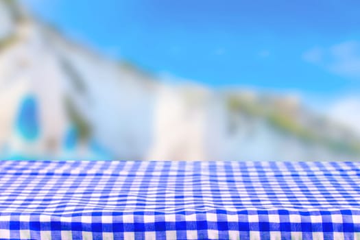 Empty table product. Empty colorful checkered tablecloth over abstract blurred natural bright background texture with space for food and product display montage.