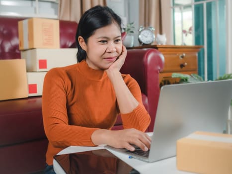Asia women working business SME online at home her checking order from laptop for customer and online delivery for ready packing, Checking orders from customers with digital laptop, Small business.
