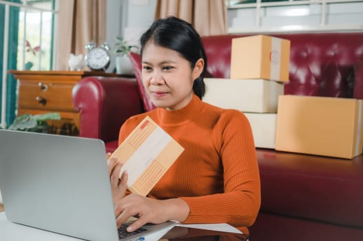 Asia women working business SME online at home her checking order from laptop for customer and online delivery for ready packing, Checking orders from customers with digital laptop, Small business.