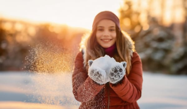 Winter fun outdoors with a girl teenager playing in the snow, making snowballs and throwing in the frosty air