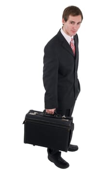 Elevated side full body view of a young man in black business suit and wide briefcase looking friendly into the camera shadowless isolated on white.