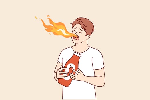Hot sauce with chili pepper or tabasco was tasted by man who was breathing fire from mouth. Guy eats spicy hot sauce or ketchup, enjoying sizzling spices for gourmets love thrills.