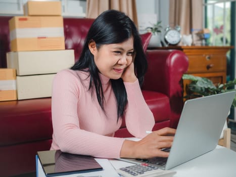 Businesswomen working business SME online at home her checking order from laptop for customer and online delivery for ready packing, Checking orders from customers with digital laptop, Small business.