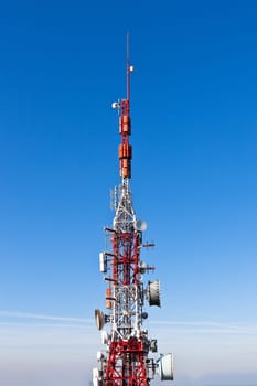 A radio communications tower with dishes against a deep blue sky