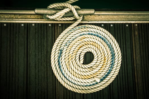 A mooring rope with a knotted end tied around a cleat on a wooden pier