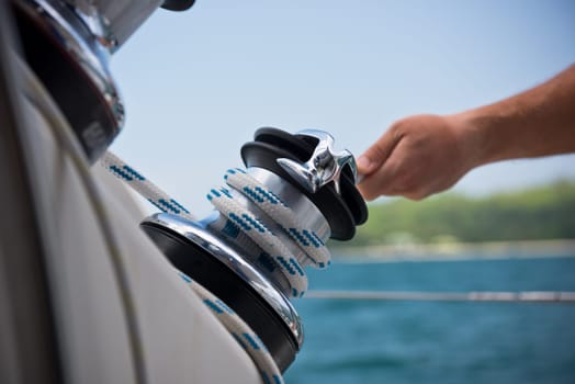 Winch and sailors hands on a sailboat. Shot with a selective focus