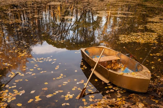 Golden wooden boat at beautiful autumn sunny day. Autumn peaceful landscape. with reflections