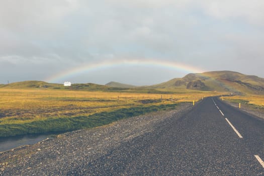 Rainbow and Endless Highway through Icelandic landscape. Filtered shot