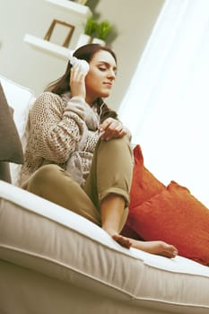 Living room, A young woman is sitting on her sofa, enjoying a moment of peace while listening to music with headphones