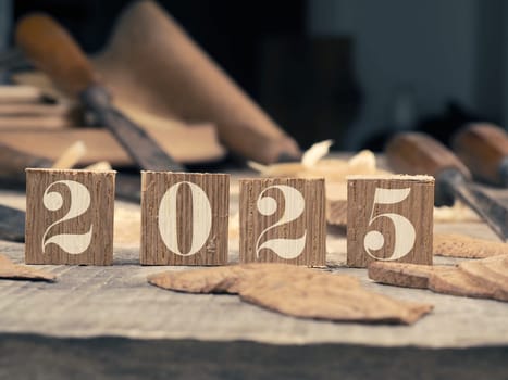 Wooden blocks with Year 2025 on a rustic workbench with chisels, wood working or creativity concept with space for text