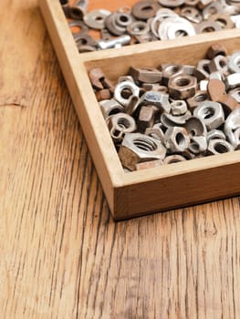 Old rusty bolts and nuts in a wooden box on a workbench