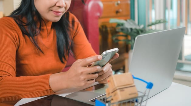 Asia women working business SME online at home her checking order from smartphone  for customer and online delivery for ready packing, Checking orders from customers with digital laptop.