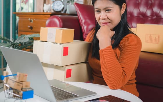Asia women working business SME online at home her checking order from laptop for customer and online delivery for ready packing, Checking orders from customers with digital laptop, Small business.