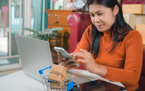 Asia women working business SME online at home her checking order from smartphone  for customer and online delivery for ready packing, Checking orders from customers with digital laptop.