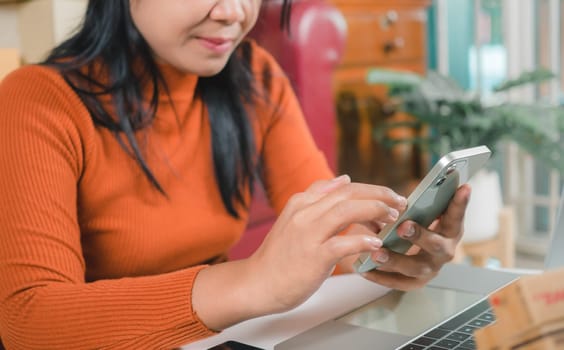 Asia women working business SME online at home her checking order from smartphone  for customer and online delivery for ready packing, Checking orders from customers with digital laptop.