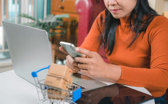 Asia women working business SME online at home her checking order from smartphone  for customer and online delivery for ready packing, Checking orders from customers with digital laptop.