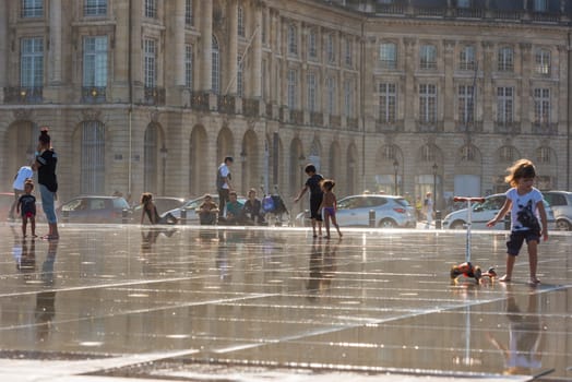 FRANCE, BORDEAUX - SEPTEMBER 20: People having fun in a mirror fountain in front of Place de la Bourse in Bordeaux, France on September 20, 2015