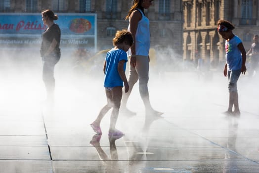 FRANCE, BORDEAUX - SEPTEMBER 20: People having fun in a mirror fountain in front of Place de la Bourse in Bordeaux, France on September 20, 2015