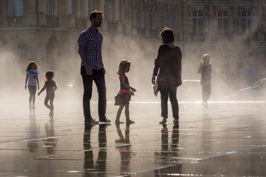 FRANCE, BORDEAUX - SEPTEMBER 20: People having fun in a mirror fountain in front of Place de la Bourse in Bordeaux, France on September 20, 2015