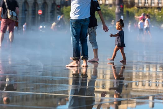 FRANCE, BORDEAUX - SEPTEMBER 20: People having fun in a mirror fountain in front of Place de la Bourse in Bordeaux, France on September 20, 2015