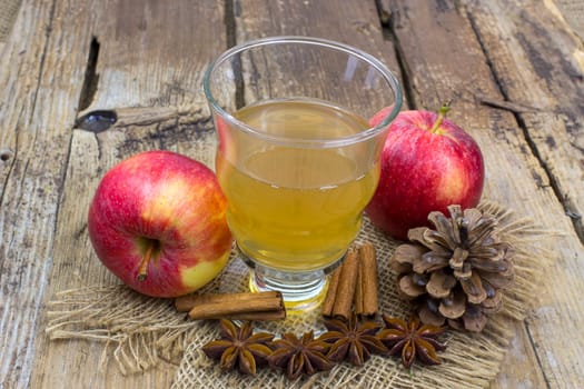 Apple juice, fresh apples, cinnamon sticks and anise stars on wooden background